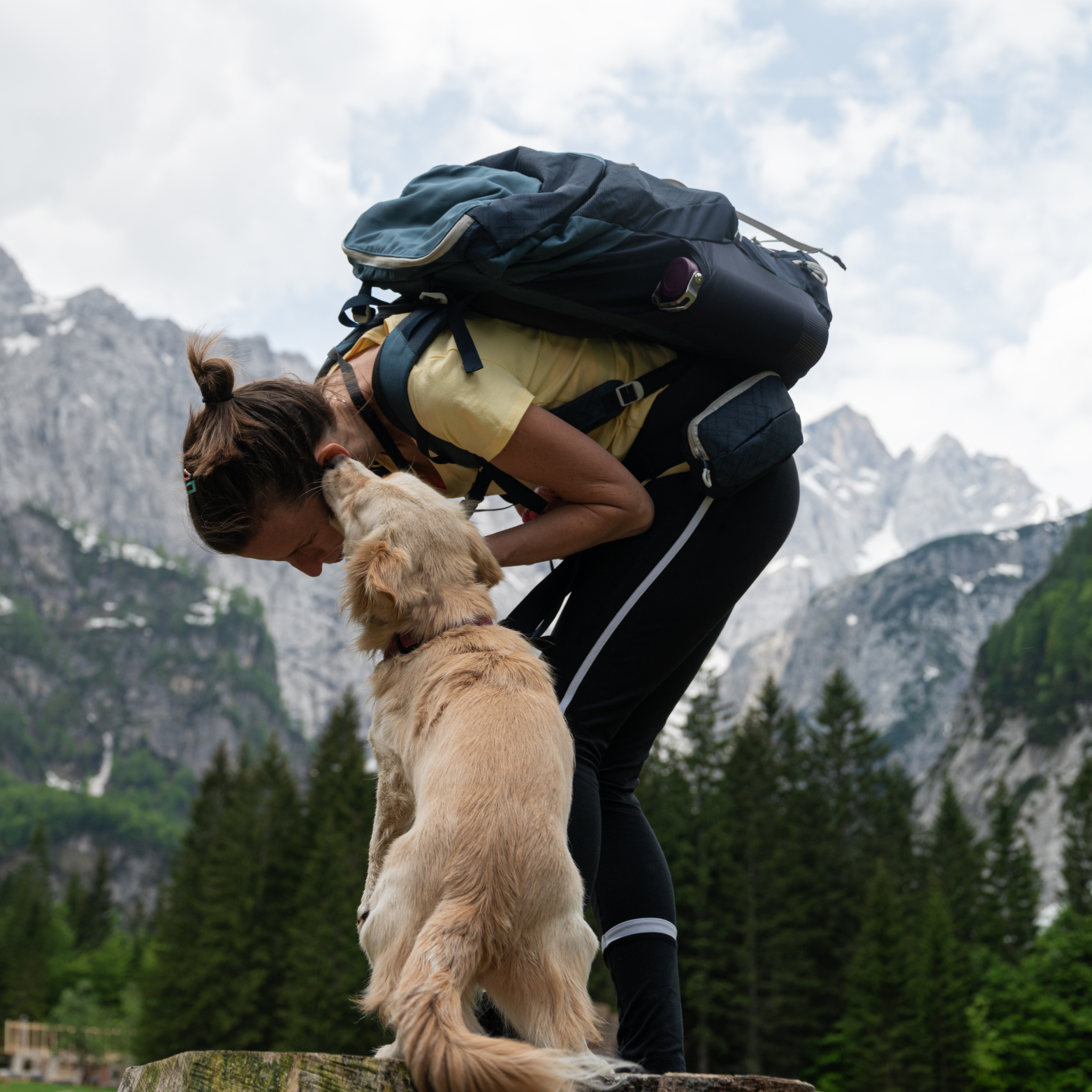 Femme en randonnée en montagne partage un moment tendre avec son chien